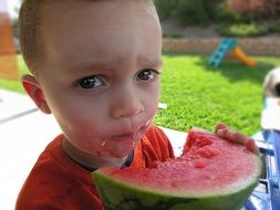 Child boy eating Watermelon outdoor close-up