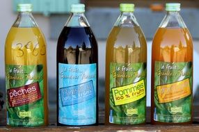 four glass bottles with multicolored citrus juices