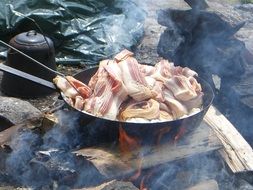 bacon fried on fire in the open air