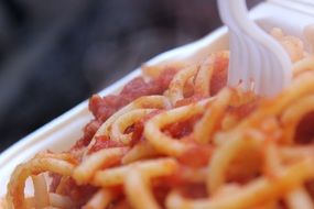 Italian spaghetti with tomato sauce in a disposable bowl