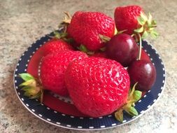 strawberries and cherries on a small plate