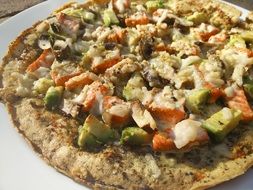 pizza with salmon and avocado on white plate