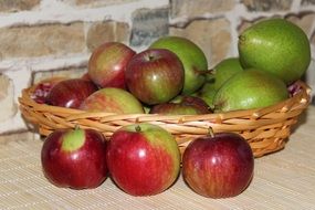 green pears and red-green apples in a wicker basket