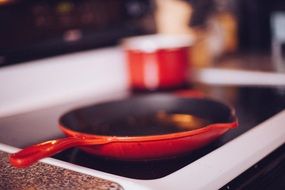 red frying pan heated on the stove in the kitchen