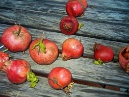 red pomegranates on a wooden surface