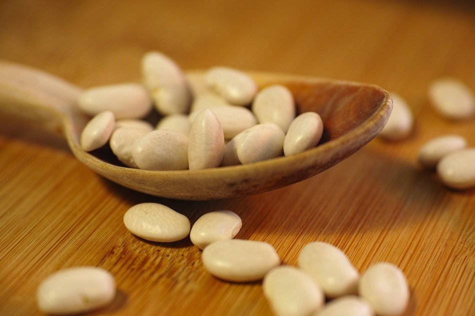 Beans in spoon on wooden table