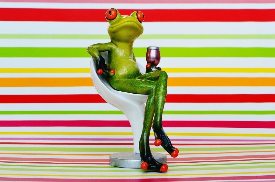 funny figurine of a frog on a chair with a glass