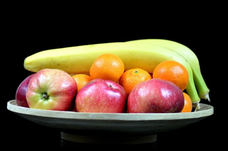 illuminated pile of fruits on plate in darkness