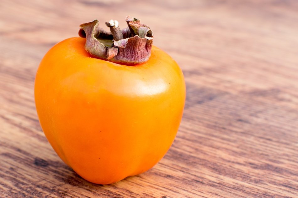 yellow persimmon on a wooden table