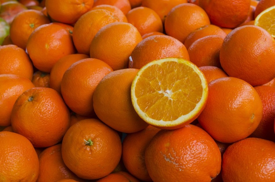 cut Orange on pile of Fruits