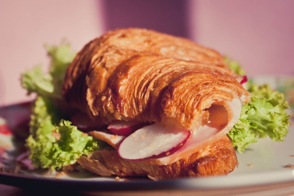 Croissant sandwich with the salami and lettuce