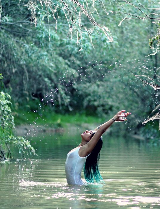 girl with long hair in the water among green vegetation