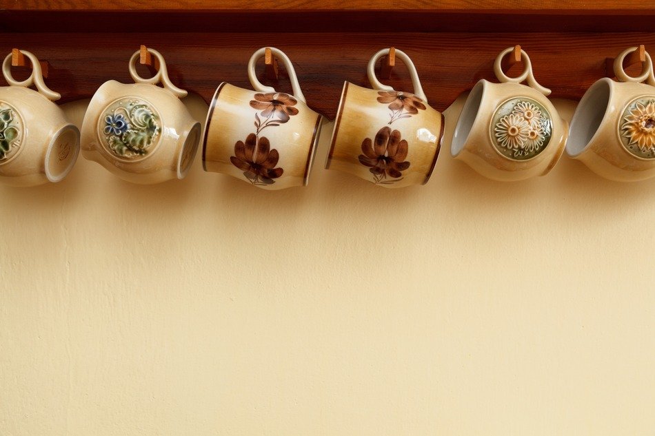 Ceramic coffee mugs hang in row