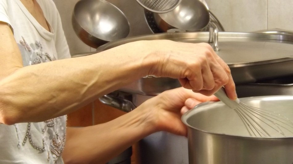 cooker stirs a whisk in the sausepan