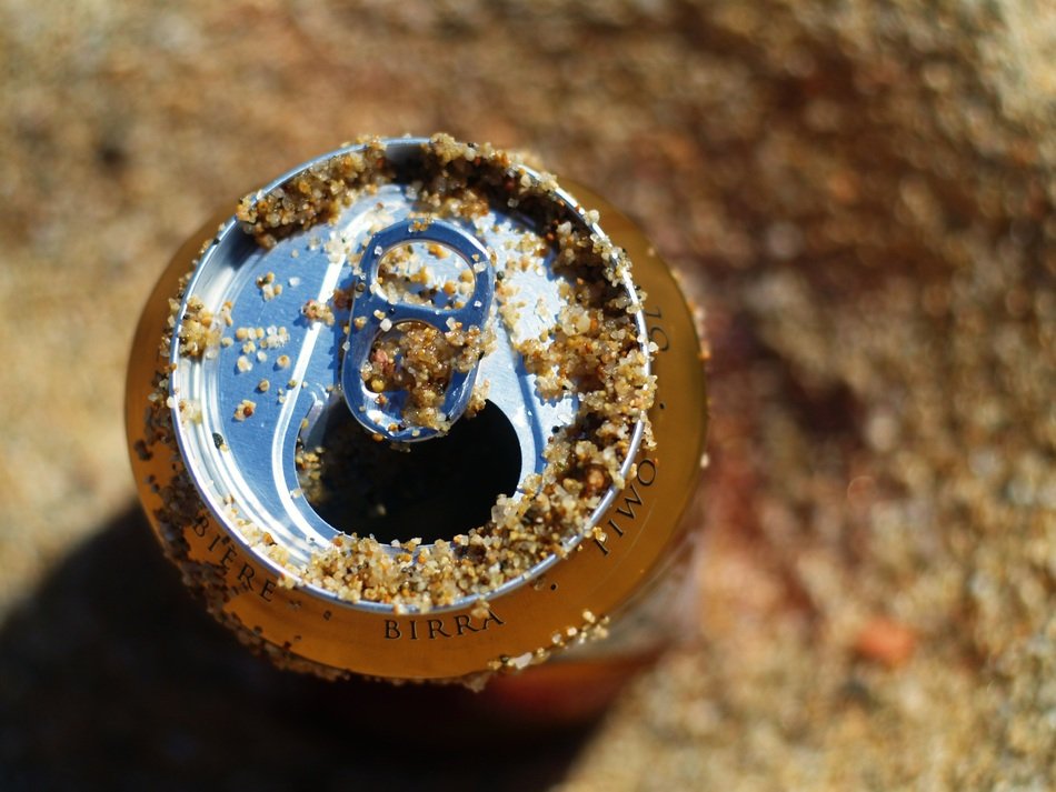 can of beer in the sand closeup