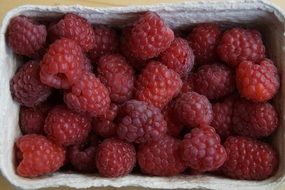 ripe raspberries in a cardboard box