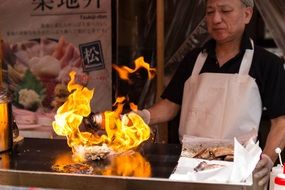 cook cooks food on fire