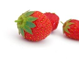 red strawberries with green ponytails on a white surface