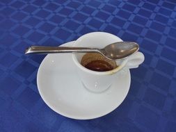 espresso in a small white cup on a blue tablecloth