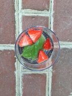 Sliced strawberries with basil in a glass