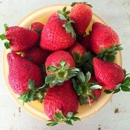 dark red ripe strawberries in a yellow plate