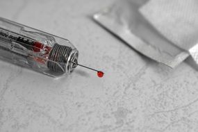 syringe with a drop of blood on the needle