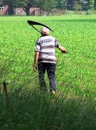 farmer with scythe on green grass