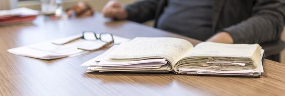 man at table with open notebook in Office