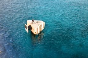 man sits on construction above water