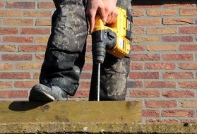 worker drills a hole with a drill