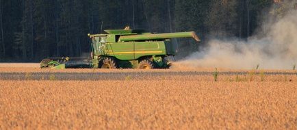 green harvester on the field is harvesting