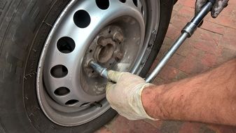 manâs hands with screwdriver at auto Wheel