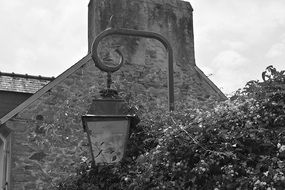 black and white photo of a lamp on a stone wall