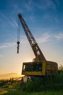 Abandoned Industrial Crane in wilderness at sunset