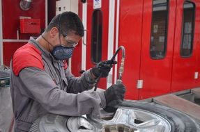 Mechanic in mask cleaning wheel rim in Workshop