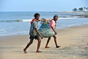 two Fishermen with Catch in net on Beach