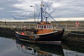fishing boat near the shore with reflection in the water
