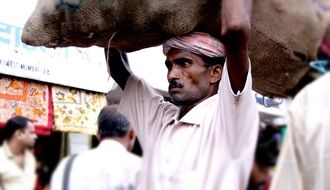 worker carries a bag over his head in india