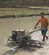 man plowing rice field with tractor, Laos