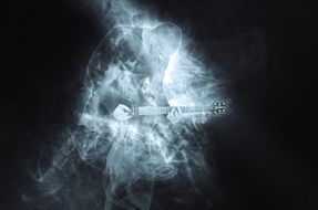 musician with guitar in on stage in smoke