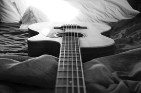 acoustic guitar on fabric in black and white image