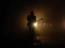 musician on stage in the shadow of lights
