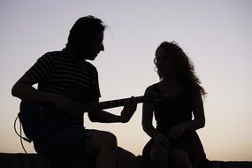 silhouettes of a young couple with a guitar