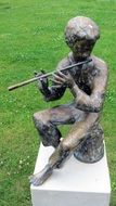 bronze sculpture of a boy with a flute in the park