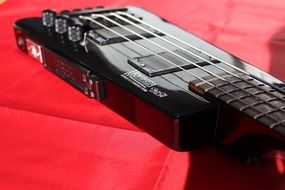 frets of the electric guitar on red closeup