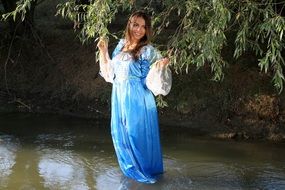 girl stands under a tree on a lake