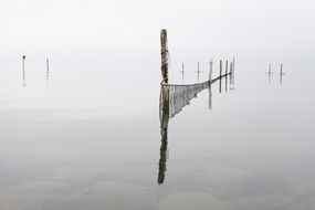 fishing Nets on wooden pillars in calm water