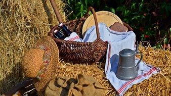 picnic basket and straw hat on a haystack