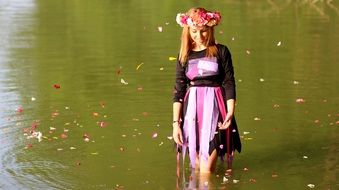 girl in a spring dress with a floral wreath on her head in a pond