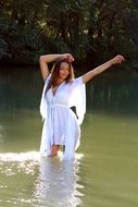 beautiful girl in a white dress in the water on a sunny day